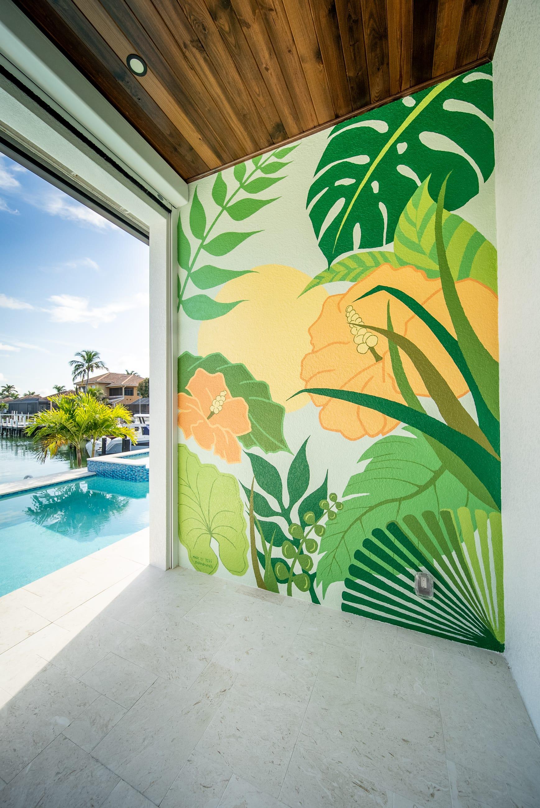 Tropical mural with monstera leaves and orange hibiscus on a poolside wall overlooking the waterfront